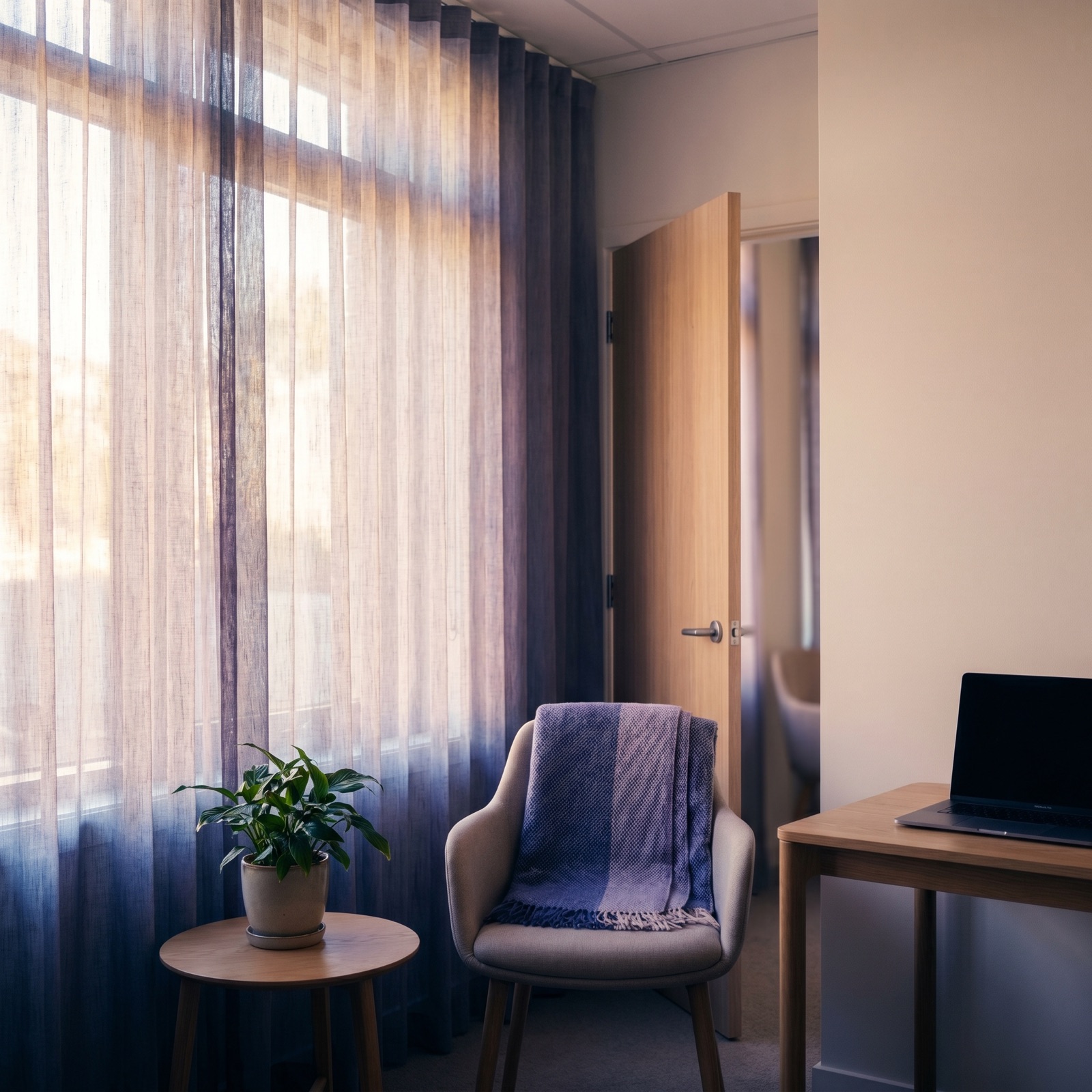 A calm room with violet daylight through sheer curtains and an empty chair — no people.